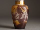 a vase with a leaf design on it sitting on a table