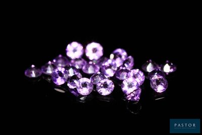 un gros plan sur un bouquet de pierres précieuses violettes posées sur une surface noire
