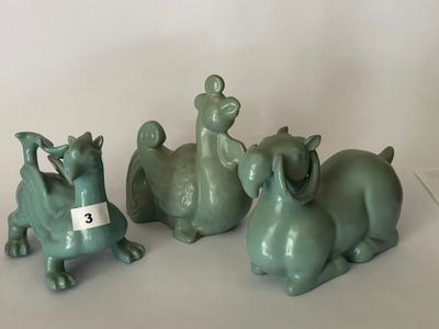 trois animaux en céramique verte assis les uns à côté des autres sur une surface blanche