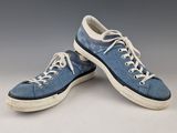 une paire de baskets bleues avec des lacets blancs, posée sur une surface blanche