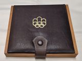 un livre en cuir marron ouvert, orné d'un symbole olympique doré
