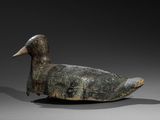 un vieux canard en bois posé sur une surface grise