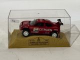a red toy car in a clear box on a wooden base