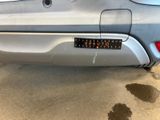 the rear end of a silver car with a sticker on it ' s bumper