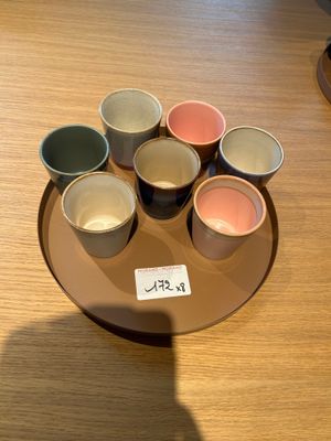 cinq tasses de couleurs différentes posées sur une assiette, sur une table