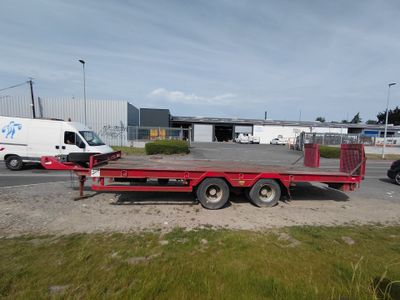 une remorque à plateau rouge garée sur le bord de la route