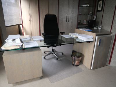 un bureau avec un plateau en verre et une chaise devant