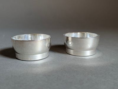 two silver cups sitting next to each other on a table