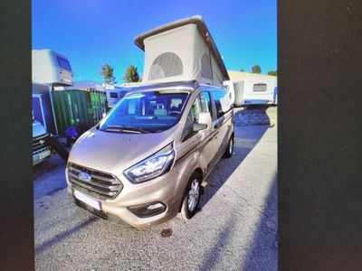 La camionnette argentée est garée sur le parking, à côté d'autres véhicules.