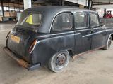 an old black car in a garage with a yellow sticker on it ' s side