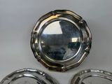 three silver plates with a mirror on top of them sitting on a table
