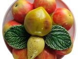 a bowl of apples and pears with leaves on it