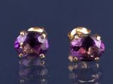 une paire de boucles d'oreilles en amethorate posées sur une surface noire