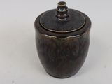 a small brown bowl with a lid on a white surface