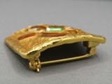 une image représentant une broche en or sertie d'une pierre verte