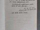 un livre ouvert, sur lequel est inscrit un poème manuscrit, posé sur une table