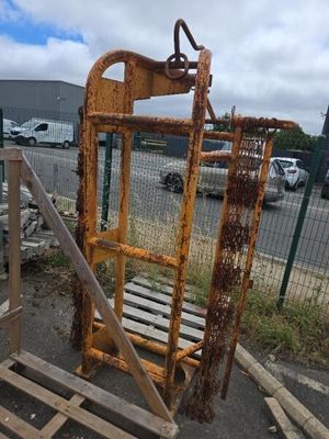une cage métallique rouillée posée sur une palette dans un parking
