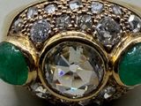 an image of a diamond and emerald ring sitting on a table