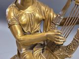 bronze statue of a woman playing a lyre on a marble base