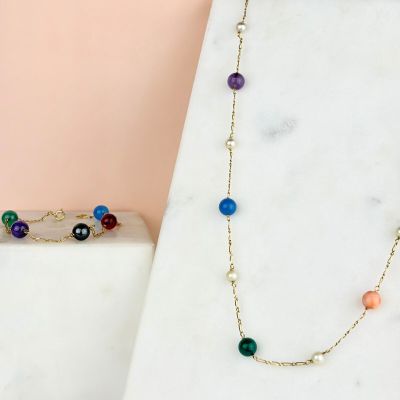 a close up of a necklace with multi colored beads on a marble surface