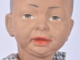 a doll with a bald head wearing a blue and white checkered dress