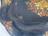 a black tray with a painting on it sitting on a table