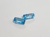 a pair of blue topazte gems on a white surface