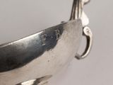 a silver bowl with a handle on a white table