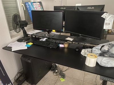 un bureau équipé de deux écrans d'ordinateur et d'un ventilateur