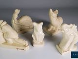 trois figurines blanches représentant des animaux et un chat sur un fond blanc