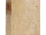 un vieux livre posé sur une table blanche à côté d'un mur blanc