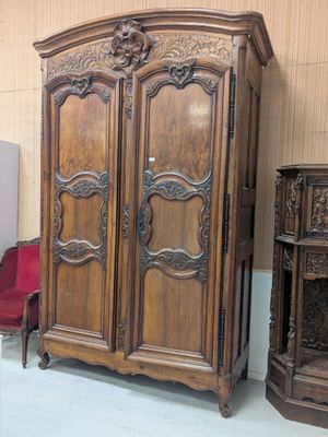 une grande armoire en bois dans une pièce où se trouve une chaise rouge