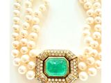 un gros plan sur un collier composé de perles et d'une émeraude