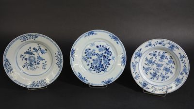 trois assiettes bleues et blanches ornées de fleurs sur fond noir