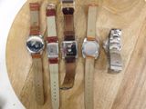 four different watches on a wooden plate on a table