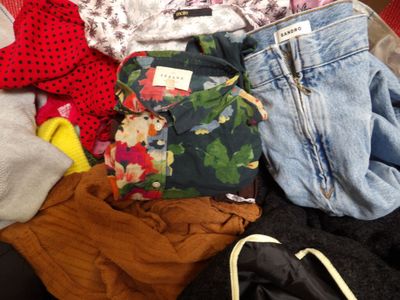 a pile of clothes that is sitting on a bed