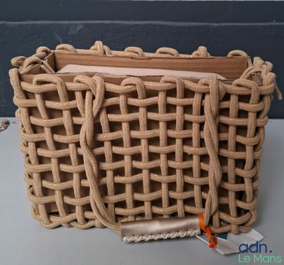 un sac tressé muni d'une poignée en bois, posé sur une table