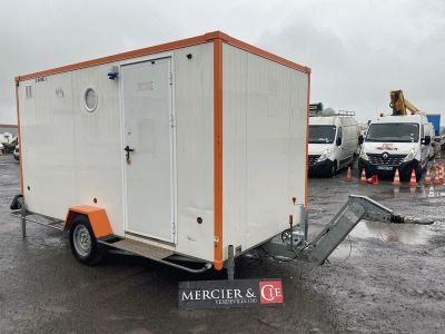 une remorque orange et blanche garée sur un parking à côté d'autres véhicules