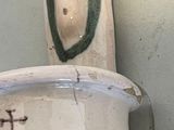 a white vase with a green handle sitting on a shelf