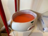 a bucket of red liquid sitting on a table next to a box of toilet paper