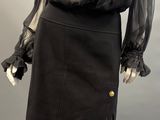 a mannequin wearing a black skirt and blouse with ruffled sleeves