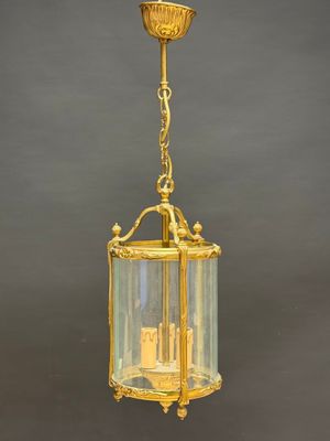 a brass and glass hanging light fixture with a castle in the center