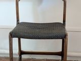 a wooden chair with a black seat on a brick floor