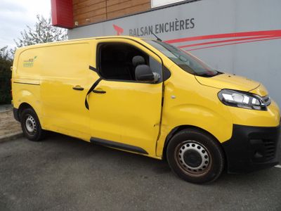 La camionnette jaune est garée devant un immeuble dont la porte est ouverte.