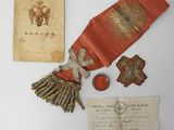 an old document with a red ribbon and other items sitting on a table