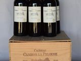 four bottles of red wine in a wooden box on a table