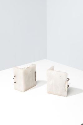 une paire de boucles d'oreilles en forme de cubes de marbre blanc posées sur une surface blanche