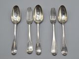 four silver spoons and a fork are lined up on a table