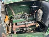 an old green car with an engine in the trunk