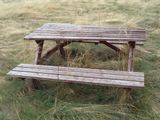 a wooden picnic table sitting in the middle of a field